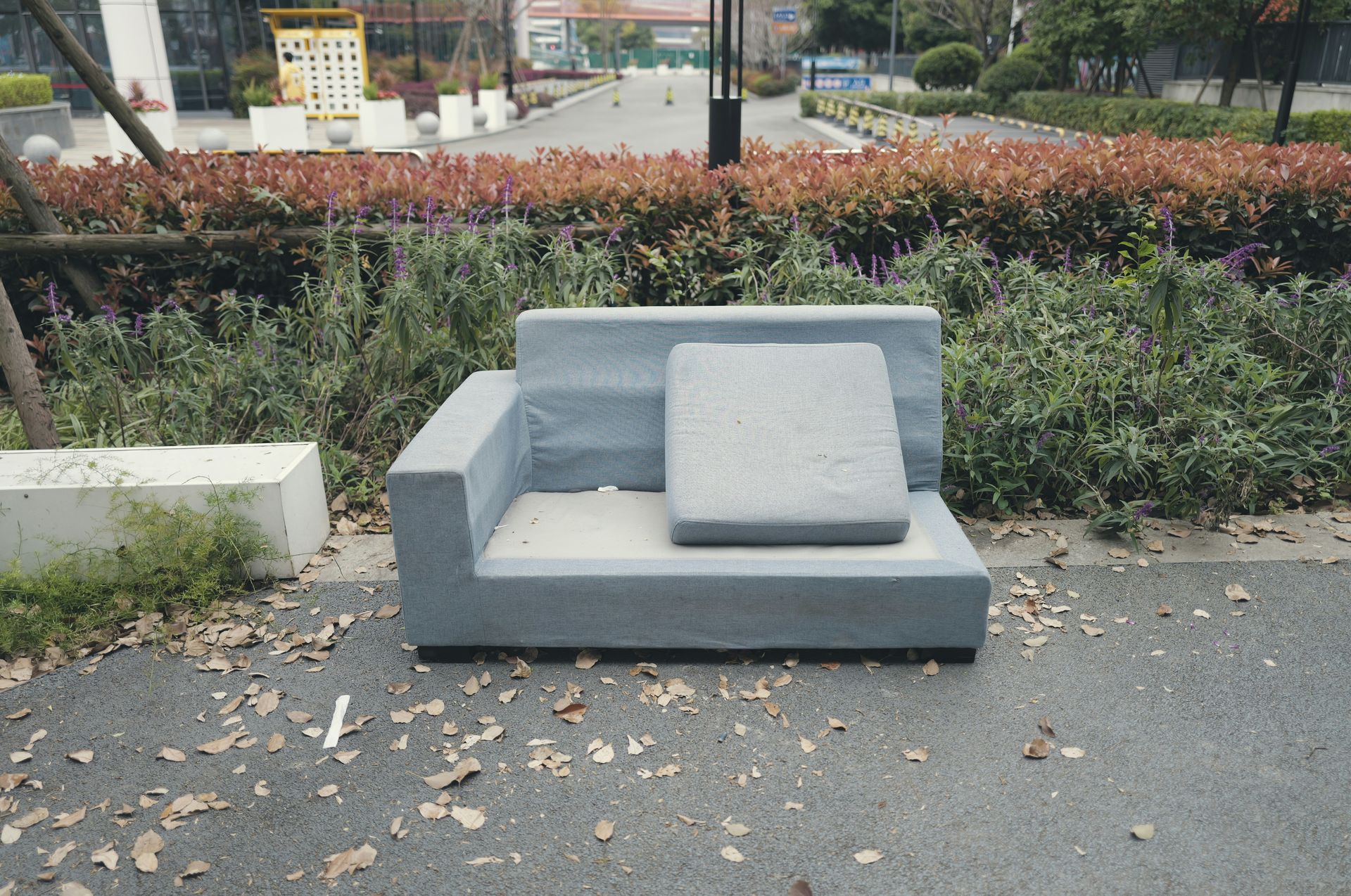 A grey sofa sits on an outdoor paved area